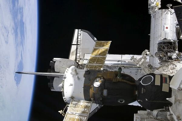 A docked Soyuz spacecraft over the docked space shuttle Atlantis
