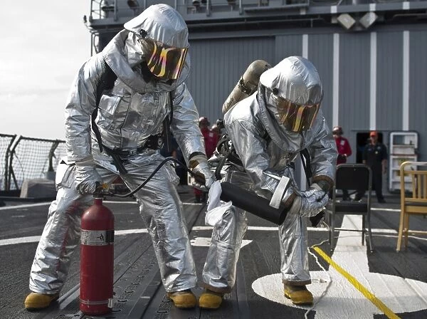 Firemen confirm a simulated fire is extinguished on the flight deck of USS Chosin