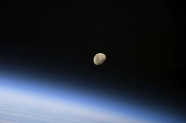 A gibbous moon visible above Earths atmosphere