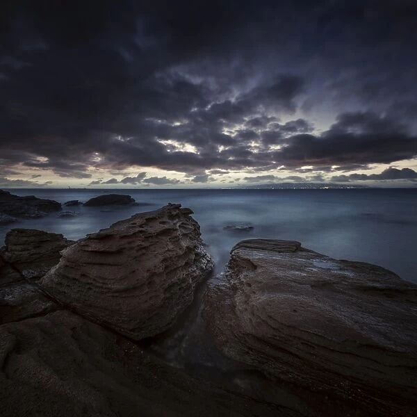 Huge rocks on the shore of a sea against stormy clouds, Sardinia, Italy