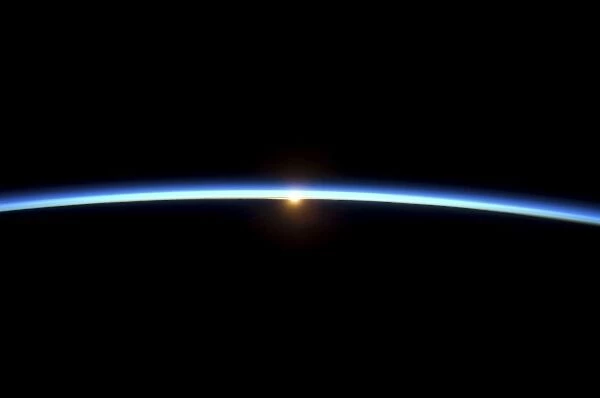 The thin line of Earths atmosphere and the setting sun