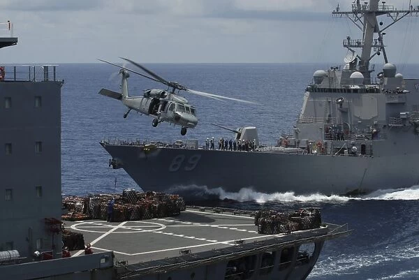 An MH-60S Knighthawk helicopter transports a pallet of supplies to USS Essex