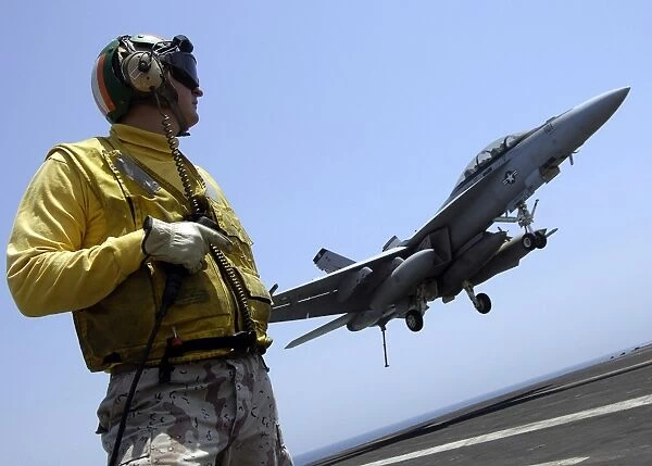 An officer observes an F  /  A-18F Super Hornet prepare for an arrested landing