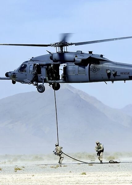 Pararescuemen descend from an HH-60 Pave Hawk helicopter