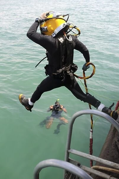 A photographer documents a Navy diver as he enters the water