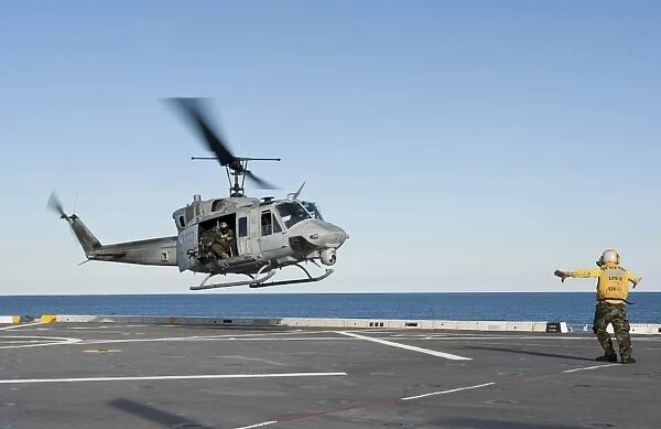 A sailor directs a UH-1N Huey helicopter aboard USS New York