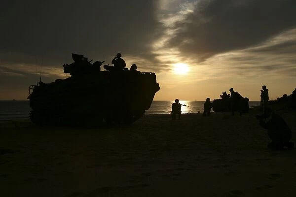 Silhouette of Marines and an amphibious assault vehicle providing security on Hwajin Beach