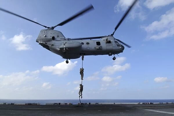 A trio of Marines fast rope from a CH-46E Sea Knight helicopter