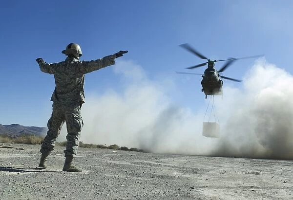 U. S. Air Force Master Sergeant guides a CH-47 Chinook to a drop site
