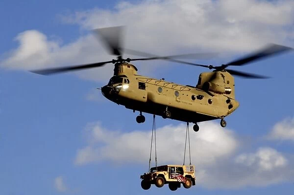 A U. S. Army CH-47 Chinook helicopter transports a Humvee