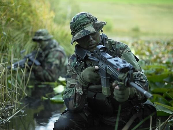 U. S. Navy SEALs cross through a stream during combat operations