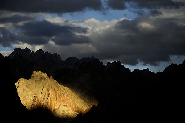 Mountain peaks and ridges in evening light, stormy skies above