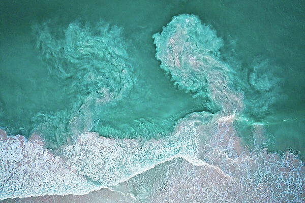 Waves crashing on beach and carrying sediments back out to sea, aerial view. The Bahamas