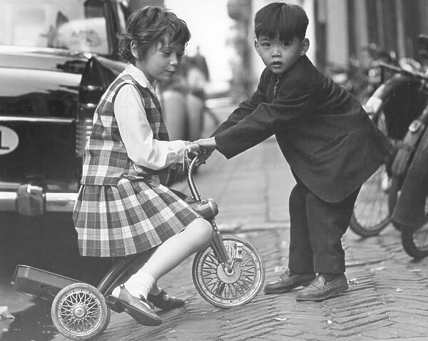 Children playing with a tricycle, c1960s