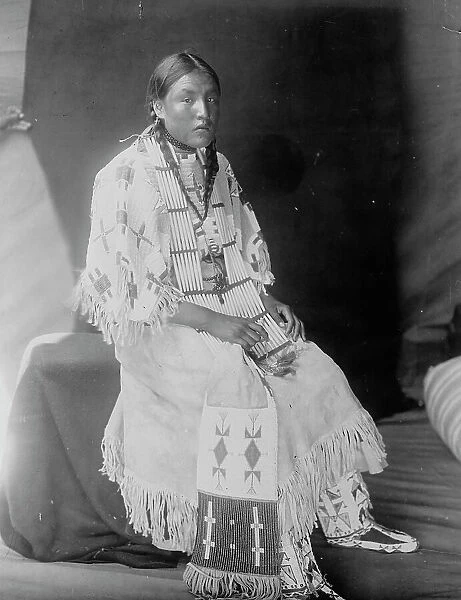 Red Elk Woman, a Sioux girl, full-length portrait, seated, facing right, c1907. Creator: Edward Sheriff Curtis