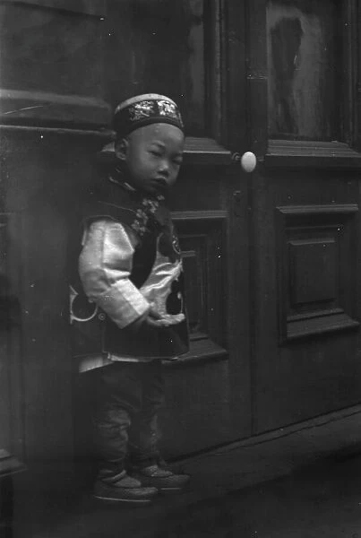 Small boy standing in front of a door, Chinatown, San Francisco, between 1896 and 1906. Creator: Arnold Genthe