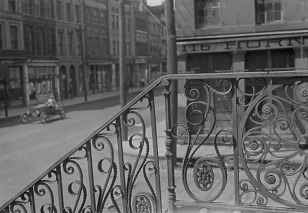 Street seen from behind the wrought iron railing of the Market Hall, Charleston... c1920-c1926. Creator: Arnold Genthe