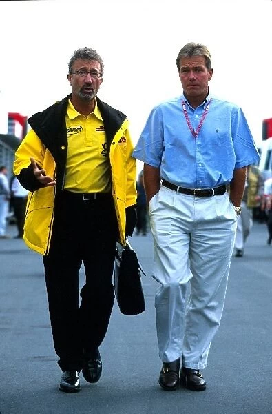 Formula One World Championship: Eddie Jordan, Jordan Grand Prix team owner, walks in discussion with Jacques Villeneuves manager Craig Pollock