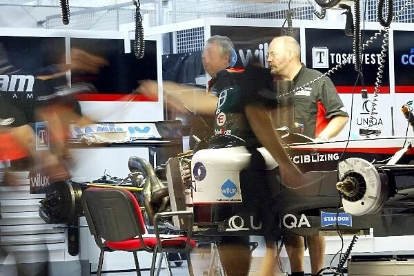 Formula One World Championship: Minardi mechanics work on the cars in the garage into the night