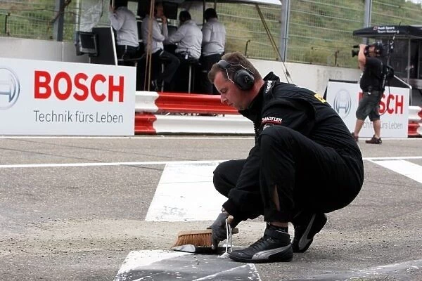 DTM. Mercedes mechanic sweeps sand from the pitlane.