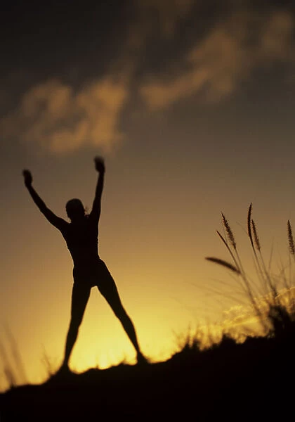 Hawaii, Silhouette Of A Woman Stretching On A Mountain Top At Sunset