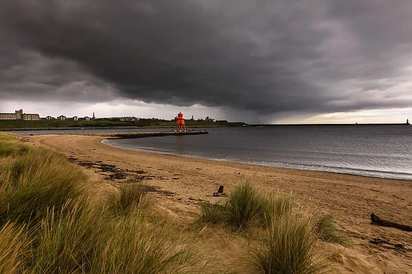 Herd Groyne Lighthouse with storm clouds overhead, and Tyne South Pier Lighthouse in the distance; South Shields, Tyne and Wear, England
