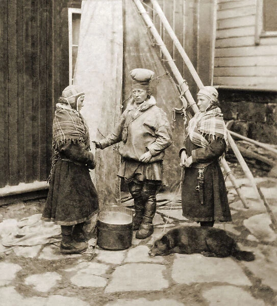 Historic image in sepia tone of women wearing shawls standing together and a dog lying on the ground with them. One woman appears to be reprimanding another, who has an embarrassed look on her face; Hammerfest, Troms og Finnmark county, Norway