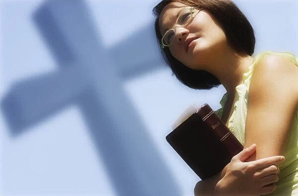 Woman Holding Bible With Cross In Background