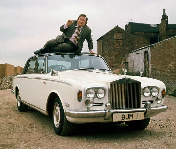 00007433 Bernard Manning sitting on roof of Rolls Royce April 1981