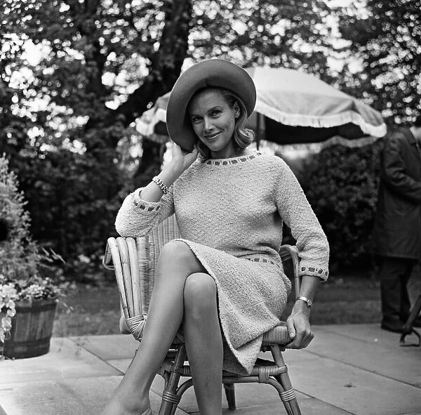 Actress Honor Blackman relaxes in her garden party outfit during the filming of