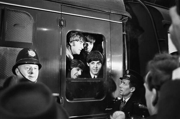 The Beatles peer from a train carriage window at Paddington Station, London