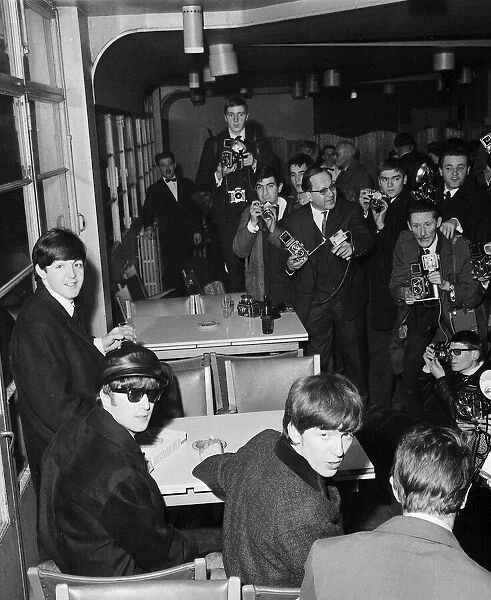 Three of The Beatles surrounded by photographers during a press conference at Le Bourget