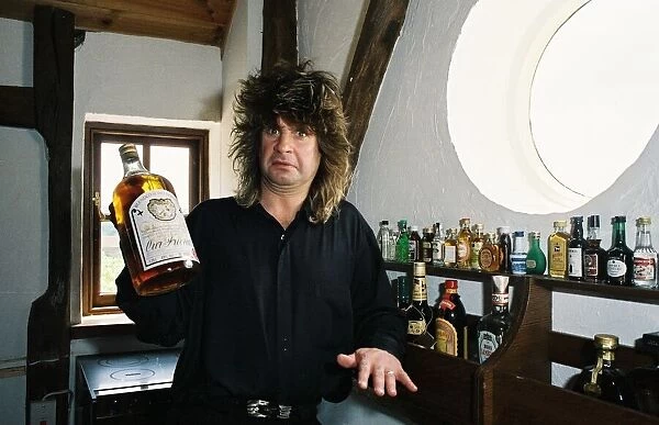 Black Sabbath singer Ozzy Osbourne holding a large bottle of whiskey at his home