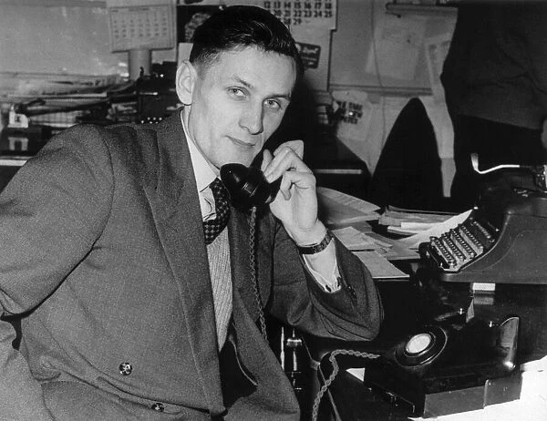 Business man talking on the telephone as he sits at a desk. Circa 1940