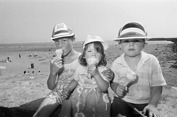 Children enjoy an ice cream as they try to keep cool on Coney Beach in Porthcawl