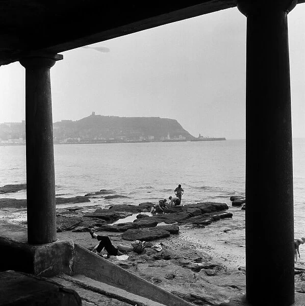 Children playing in the sea at Scarborough while a man takes a nap