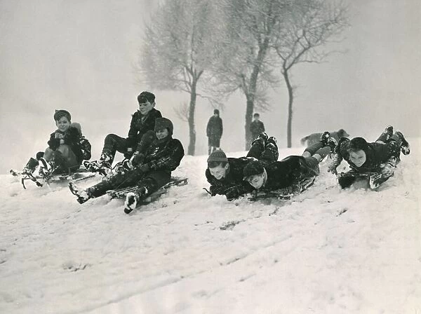 Children sledging down a hill in snow smiling and laughing after a havy snowfall