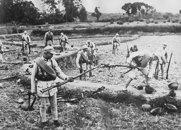 Chinese soldiers pick up the discarded weapons of Japanese soldiers who have fled