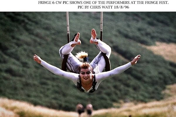 Edinburgh Fringe Festival performer acrobat hanging onto swing with legs arms