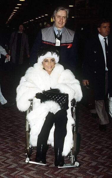 Elizabeth Taylor Jan 1987 wearing White Fur coat in wheelchair at Heathrow Airport