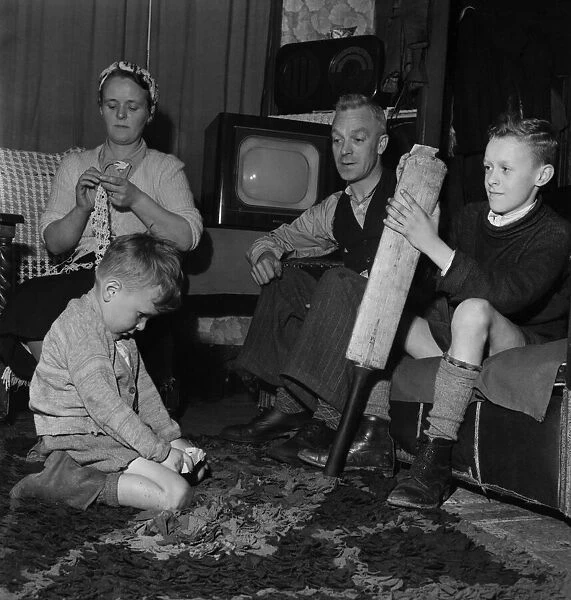 Family Life in Oldham 1952. Mother sews while father watch his youngest son play