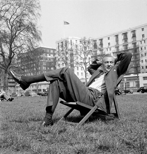 Gary Cooper sitting on a deck chair in London - April 1955 English flag in