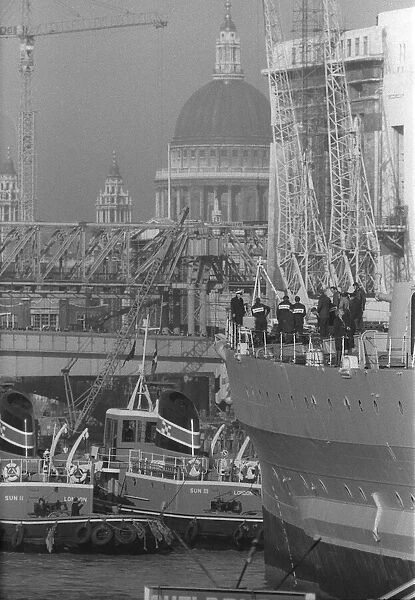 HMS Belfast sailing up the Thames passing St Pauls Cathedral to her mooring in the Pool