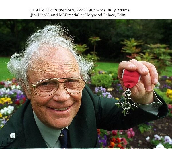 Jim Mcoll holding MBE medal at Holyrood Palace