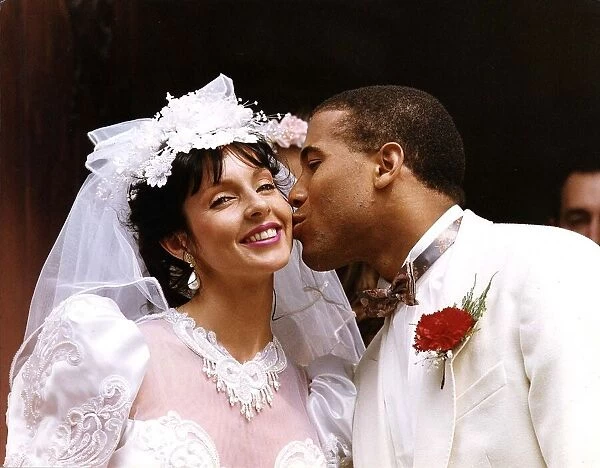 John Barnes and his bride Suz, both dressed in white, share a kiss after their wedding