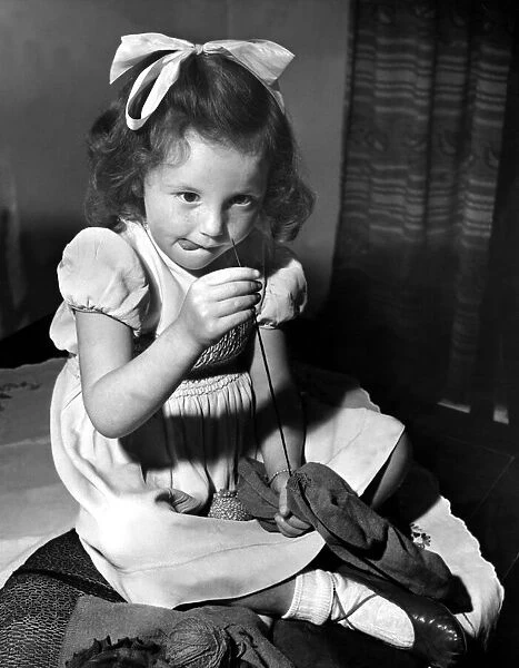 Little Hazel Robson of Newcastle, has a go at repairing a hole in a sock