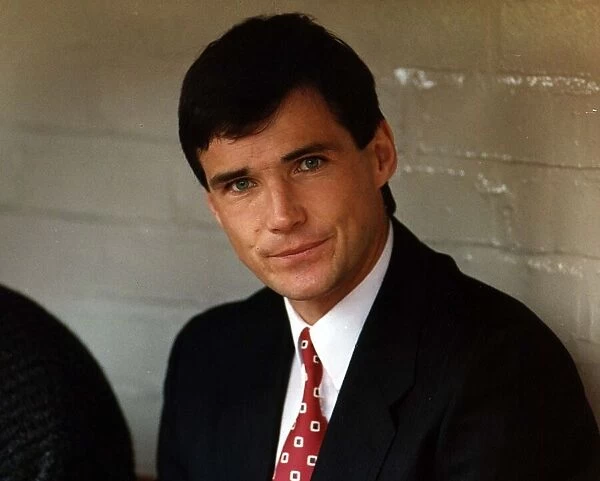 Liverpool footballer Alan Hansen dressed in suit and tie as he sits on the bench