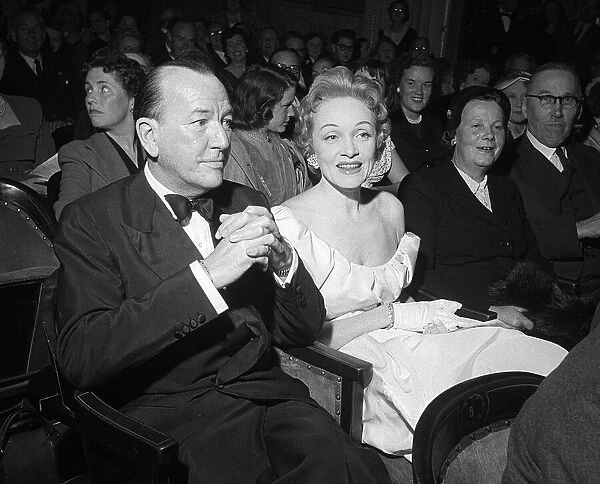 Marlene Dietrich sitting in the stalls of the Globe Theatre with Noel Coward whose play