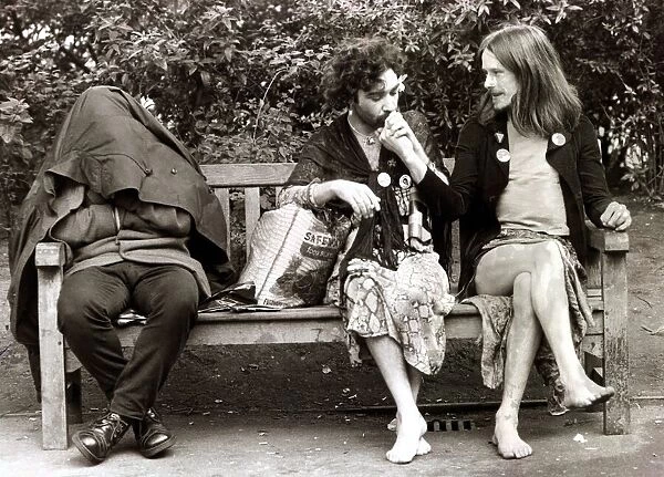 Men dressed as women sitting on a park bench as they take a break from the gay pride
