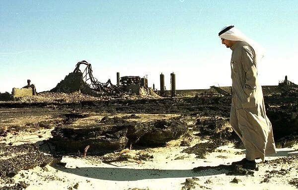 An oil worker walks amongst the wreckage of an oil containment centre destroyed by Iraq
